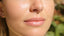 Woman with radiant, dewy skin bathed in natural light.