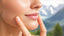 Woman with radiant skin touching her cheek.